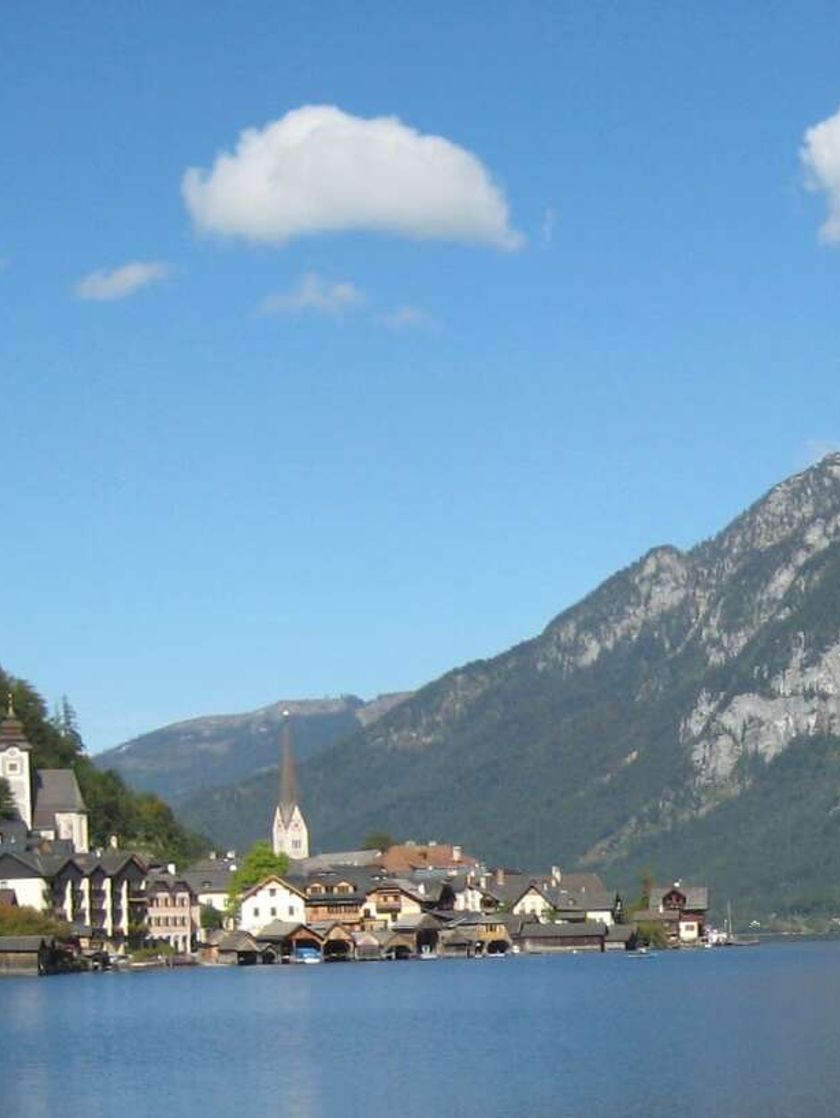 A quaint village on the shores of a lake with steep mountains behind.